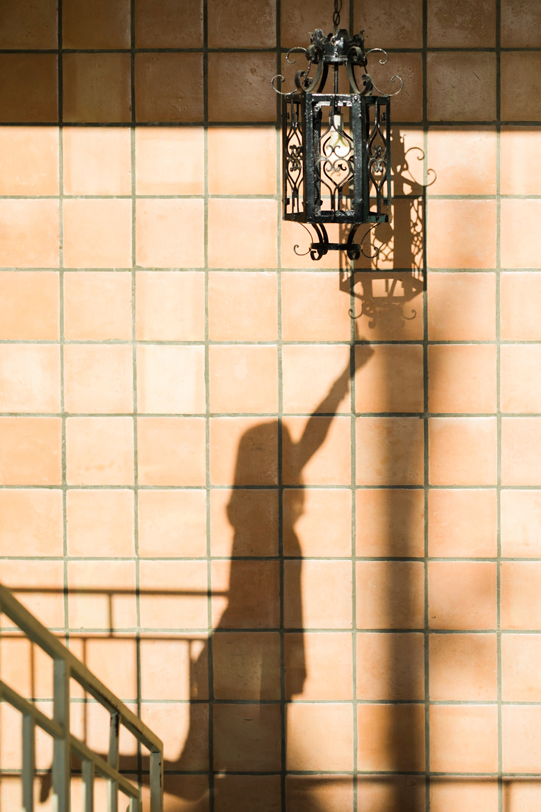 shadow of a girl touching chandelier on a Satillo tile wall